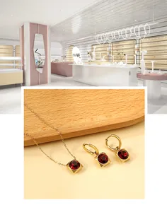 Detalle de conjunto de joyas doradas con collar y pendientes de piedras rojas en cubo