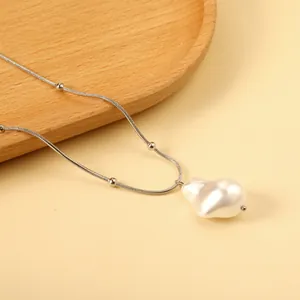 Baroque pearl pendant necklace with silver snake chain displayed on a wooden tray