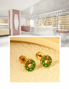 Close-up of Christmas wreath stud earrings with green enamel and red bow detail