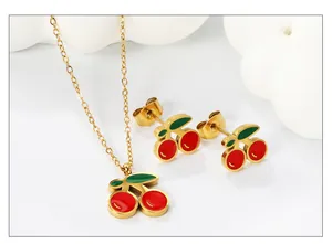 Nahaufnahme von Kirsch-Schmuckset mit Emaille-Halskette und Ohrringen auf Goldbasis
