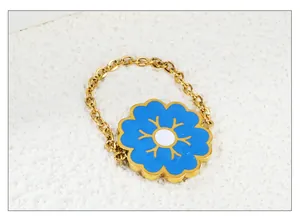 Detail of gold chain ring featuring a blue enamel flower with a starburst center charm