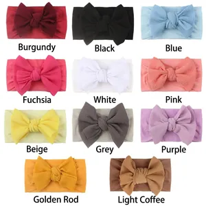 Flat lay of soft waffle knit baby headbands with large bows in eleven vibrant colors
