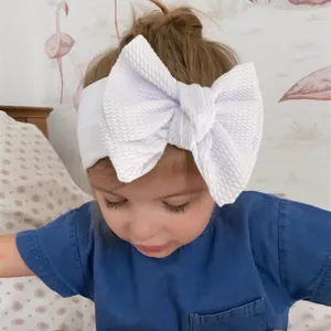 Detail of white waffle texture bow on a soft elastic nylon headband for babies
