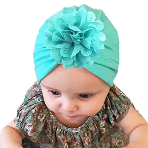 Close-up of mint green baby turban with a delicate lace flower for summer photography