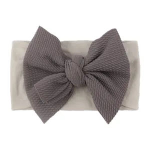Detailed shot of baby nylon headband featuring textured charcoal bow and soft elastic band