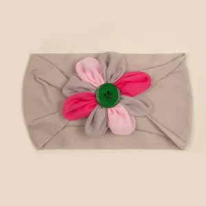 Dettaglio della fascia neonato in nylon con fiore in tessuto colorato e bottone verde
