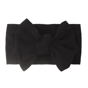 Detail of soft black nylon baby headband with a large bow showing ribbed elastic texture