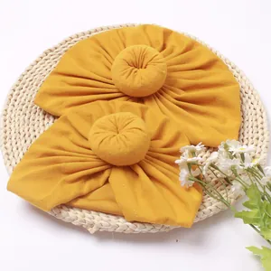Close-up of two bright yellow baby donut hats made of soft elastic knit on a woven mat