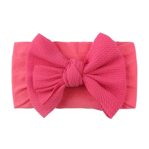 Detail of rose red nylon baby headband featuring soft ribbed knit fabric and large bow