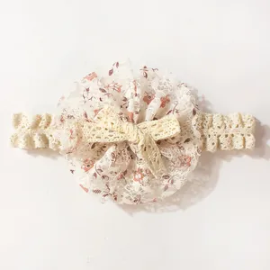 Detail van babyhoofdband met bloemenkant, grote ronde bloem en een geweven strikje
