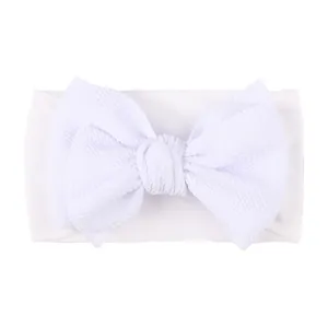 Detailed view of white nylon baby headband with large textured waffle bow detail