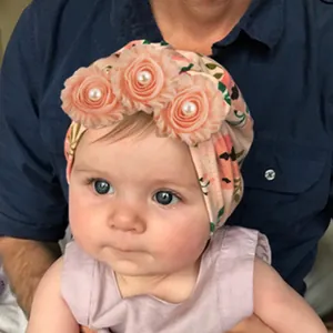 Detail of light pink baby turban featuring three layered chiffon flowers and pearls