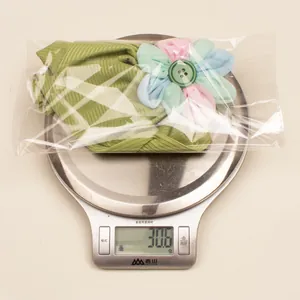 Gros plan d'un bonnet turban bébé vert clair pesant 30,6 g sur une balance numérique