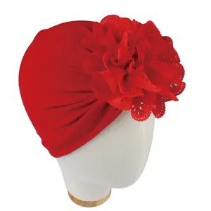 Détail d'une fleur évidée rouge sur un bonnet turban pour bébé en coton doux