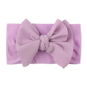 Detail of purple waffle texture nylon baby headband featuring a large soft bow decoration