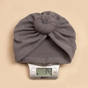 Detailopname van grijze baby tulband muts op weegschaal met gewicht van 34,2 g