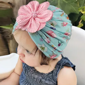 Detail einer Baby-Turbanmütze mit Blumenmuster, rosa 3D-Blume und Perlenverzierung
