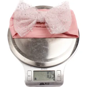Detail view of a pink nylon bow headband on a digital scale weighing exactly 10.9 grams