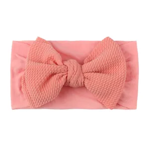 Close-up of soft pink baby headband with large waffle knit bow and wide elastic band