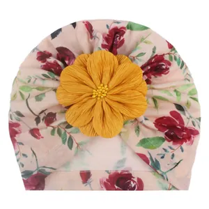 Detail der Baby-Turbanmütze mit rosa Blumendruck und einer großen gelben Stoffblume