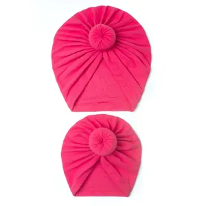 Detailed view of pink donut knot turbans showing soft pleated fabric and elastic texture