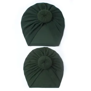 Detail of two dark green donut knot baby turbans in soft stretch knit fabric