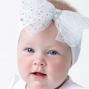 Detail of white nylon headband for babies featuring a sequined mesh bow accessory