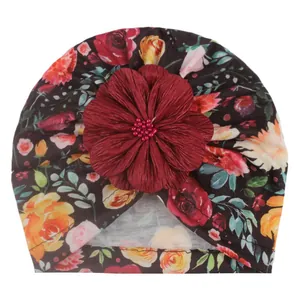 Baby Turban-Mütze mit Blumenmuster, großer roter Stoffblume und rosa Perlen auf weißem Grund