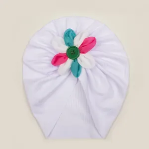 Détail de la maille côtelée blanche et fleur colorée sur le bonnet turban pour bébé