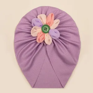 Détail du bonnet turban violet pour bébé avec fleur en tissu colorée et bouton vert