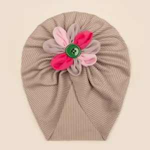 Détail macro du turban bébé côtelé avec une fleur en tissu colorée et un bouton décoratif