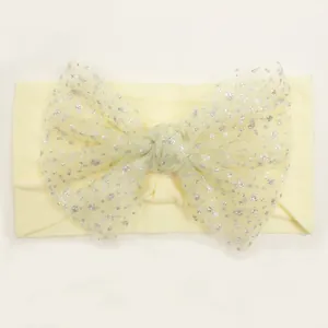 Detail of cream baby headband featuring a soft nylon mesh bow with silver glitter polka dots