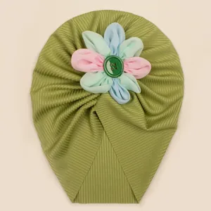 Détail de la texture côtelée et fleur multicolore sur le bonnet turban vert bébé