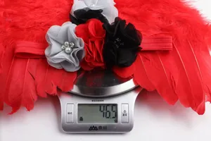 Dettaglio della fascia di piume rosse con fiore di gioiello pesata su bilancia digitale