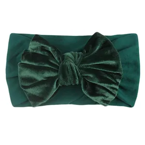 Detail of forest green velvet headband with a large bow showing soft fabric texture