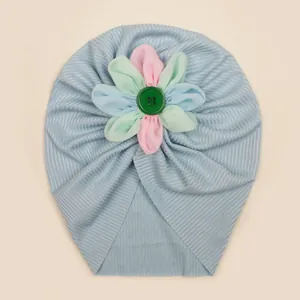 Détail du turban pour bébé en maille côtelée bleu clair avec une fleur en tissu colorée
