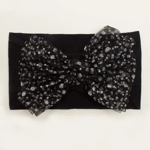 Detail of baby headband featuring large black mesh bow with silver glitter dots