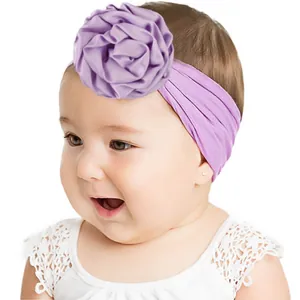 Gros plan d'un bandeau violet en nylon pour bébé avec une grande fleur en satin satiné