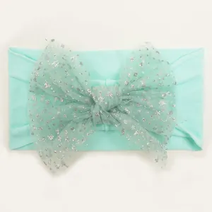 Close-up of mint green nylon baby headband with a large sequined mesh bow detail