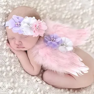 Dettaglio del set fotografico neonato con ali di piume rosa e fascia floreale elastica