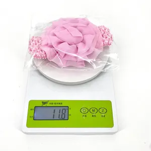 Gros plan d'un bandeau pour bébé en mousseline rose sur une balance pesant 11,8 g