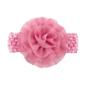 Détail de la fleur en mousseline rose vif sur un bandeau élastique pour bébé