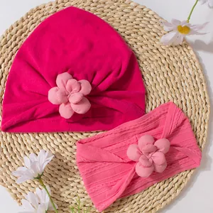 Détail de l'ensemble bonnet turban et bandeau tricoté pour bébé avec fleurs