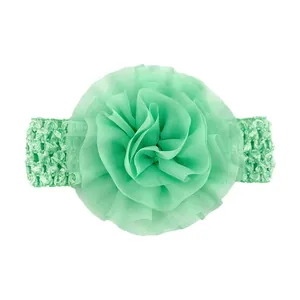 Vue détaillée d'une fleur en mousseline vert menthe et d'un bandeau en crochet pour bébé