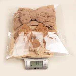 Détail de 5 bandeaux bébé en tricot aux tons café sur une balance affichant 102,3g