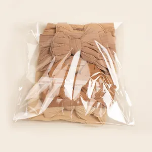 Lot de trois bandeaux à nœud pour bébé aux tons terreux sous emballage plastique