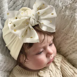 Detail eines Baby-Turbans mit großer goldener Punkte-Schleife und Faltenstruktur