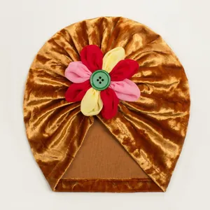 Détail du turban en velours pour bébé avec fleur en tissu coloré et bouton décoratif