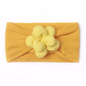 Détail du bandeau bébé en tricot de nylon jaune avec applique florale décorative douce
