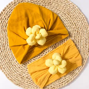 Détail d'un ensemble bonnet et bandeau jaune gingembre pour bébé avec fleurs en tissu